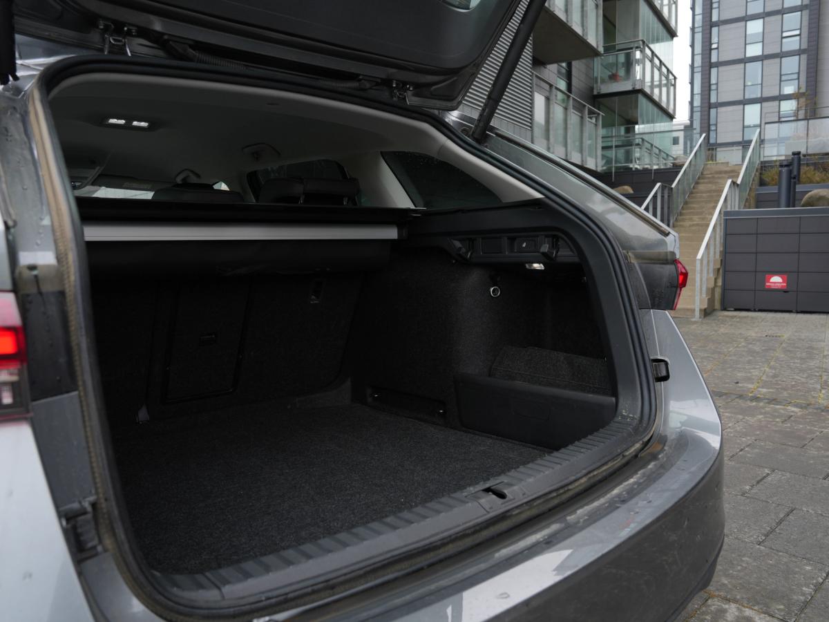 Farangursrými Octavia Wagon Skoda Octavia-stationbíll með opið skott, farangurshlíf og byggingar í bakgrunni