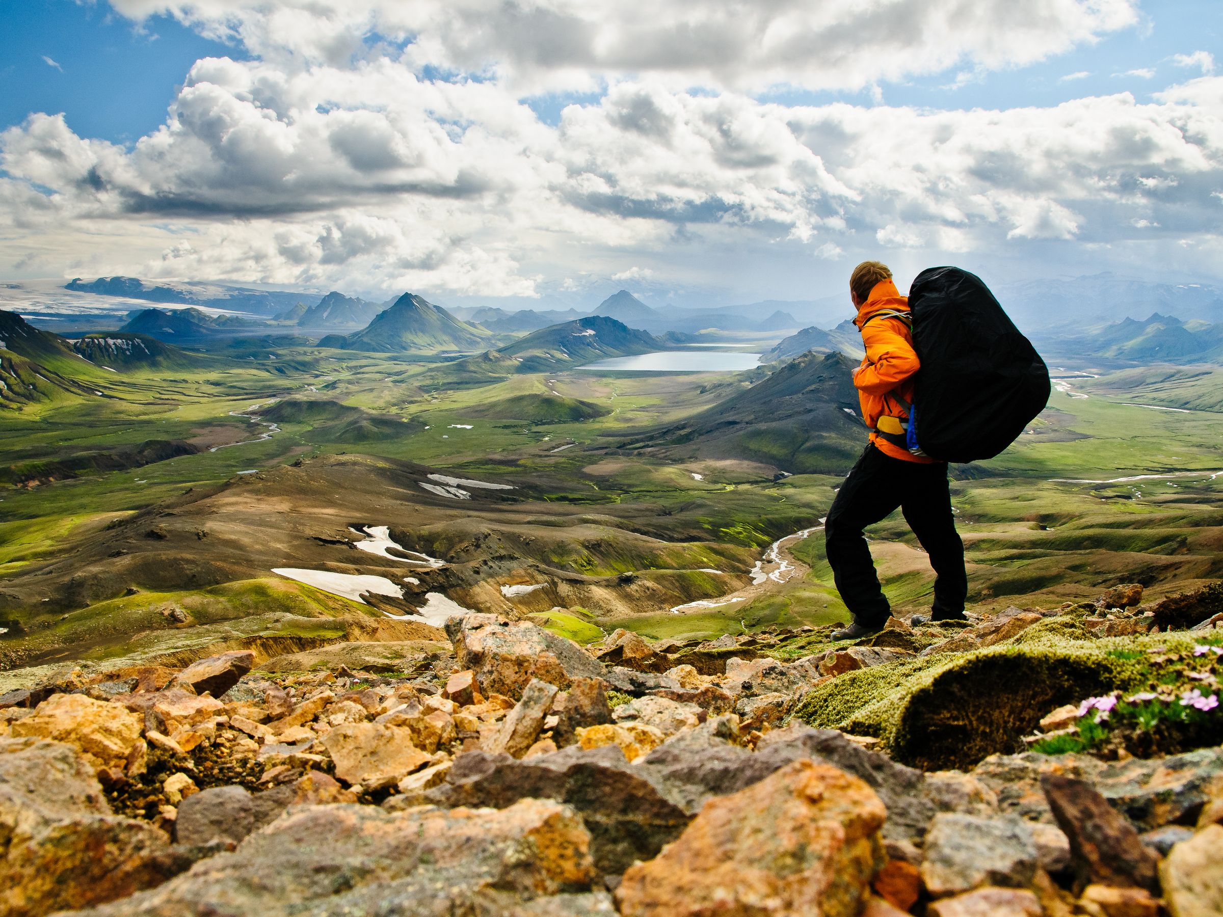 a person with a backpack is standing on top of a mountain .