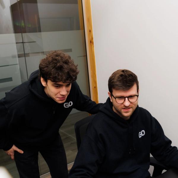 two men are looking at a computer screen in a room .