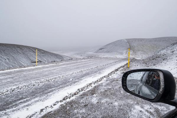 a car is driving down Kjölur road all covered in snow