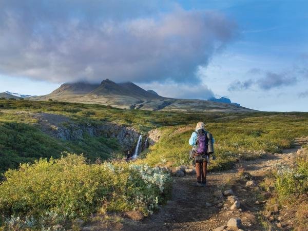 Person hiking a path on a green valley