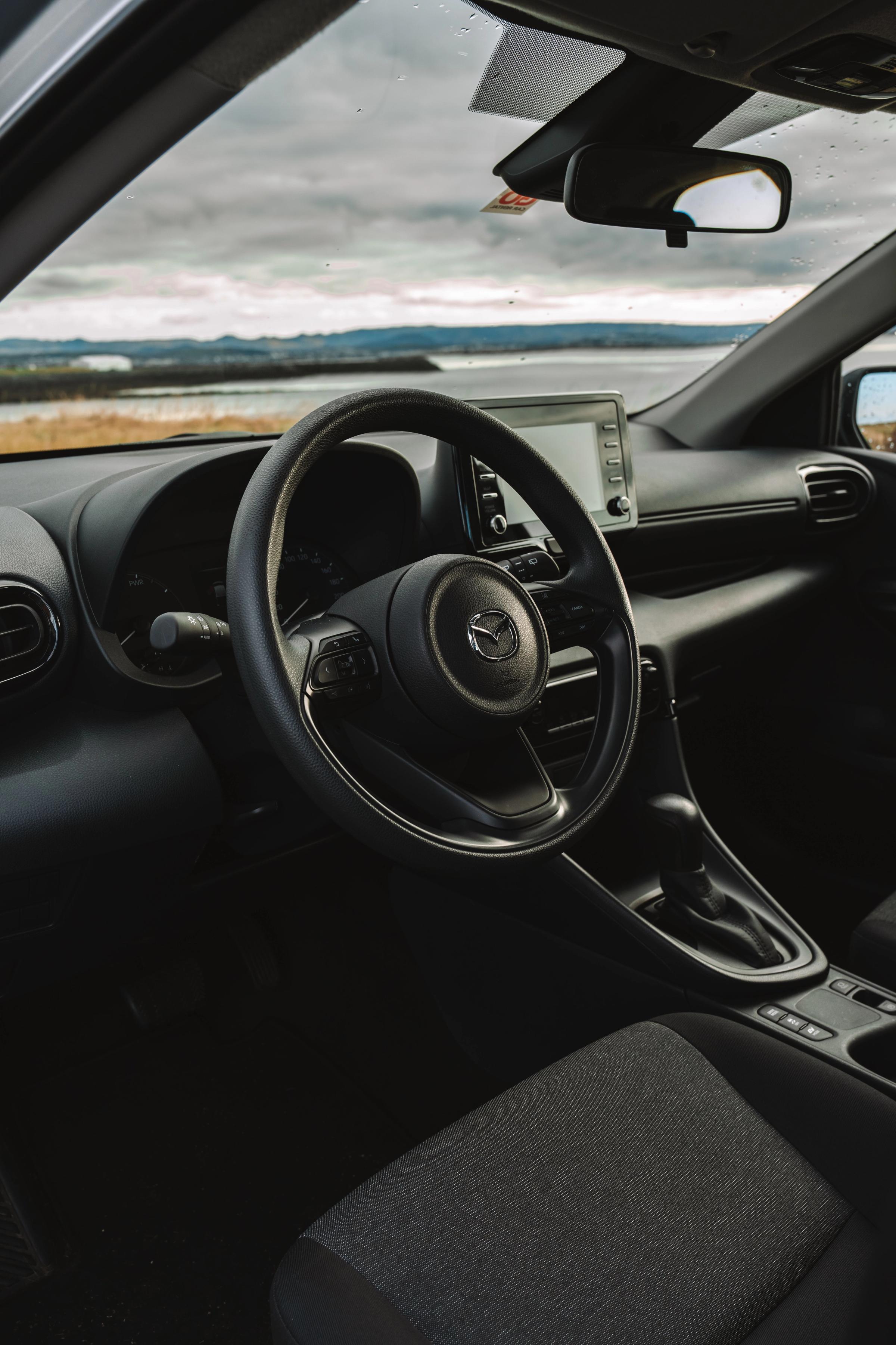 Toyota Yaris interior view of steering wheel and dashboard with coastal view outside