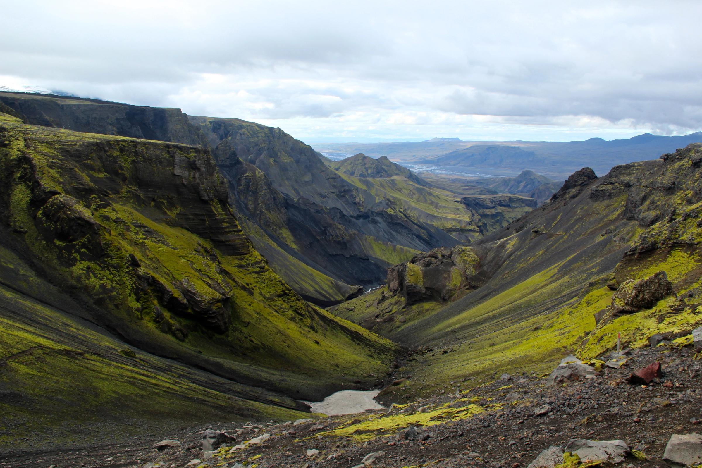 a valley filled with green grass and mountains in the background