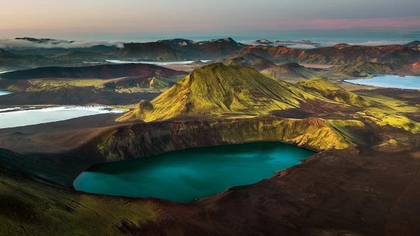 an aerial view of a lake in the middle of a mountain surrounded by mountains .