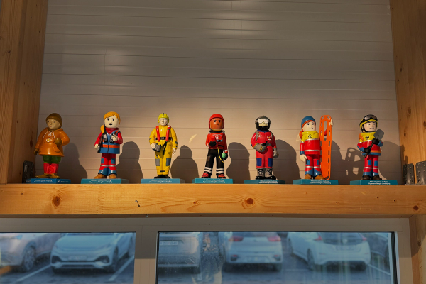 Eight colorful figurines of rescue workers displayed on a wooden shelf.