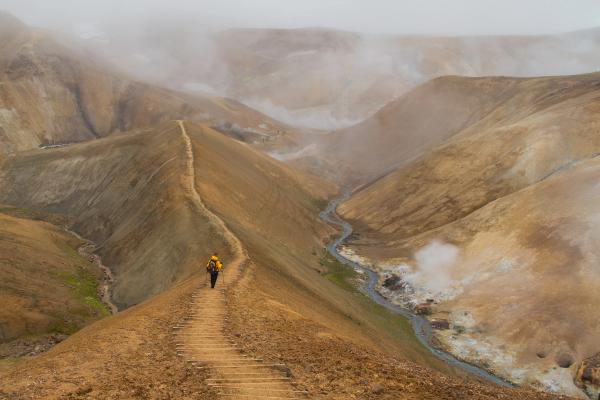 a person is walking down a dirt path in the mountains, Kerlingarfjöll