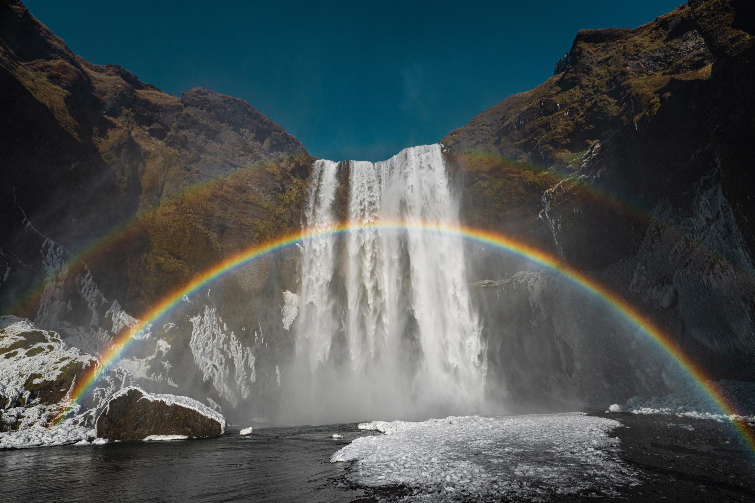 un arcoíris completo frente a una cascada