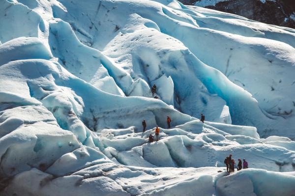 a group of people are standing on top of a large iceberg in iceland.