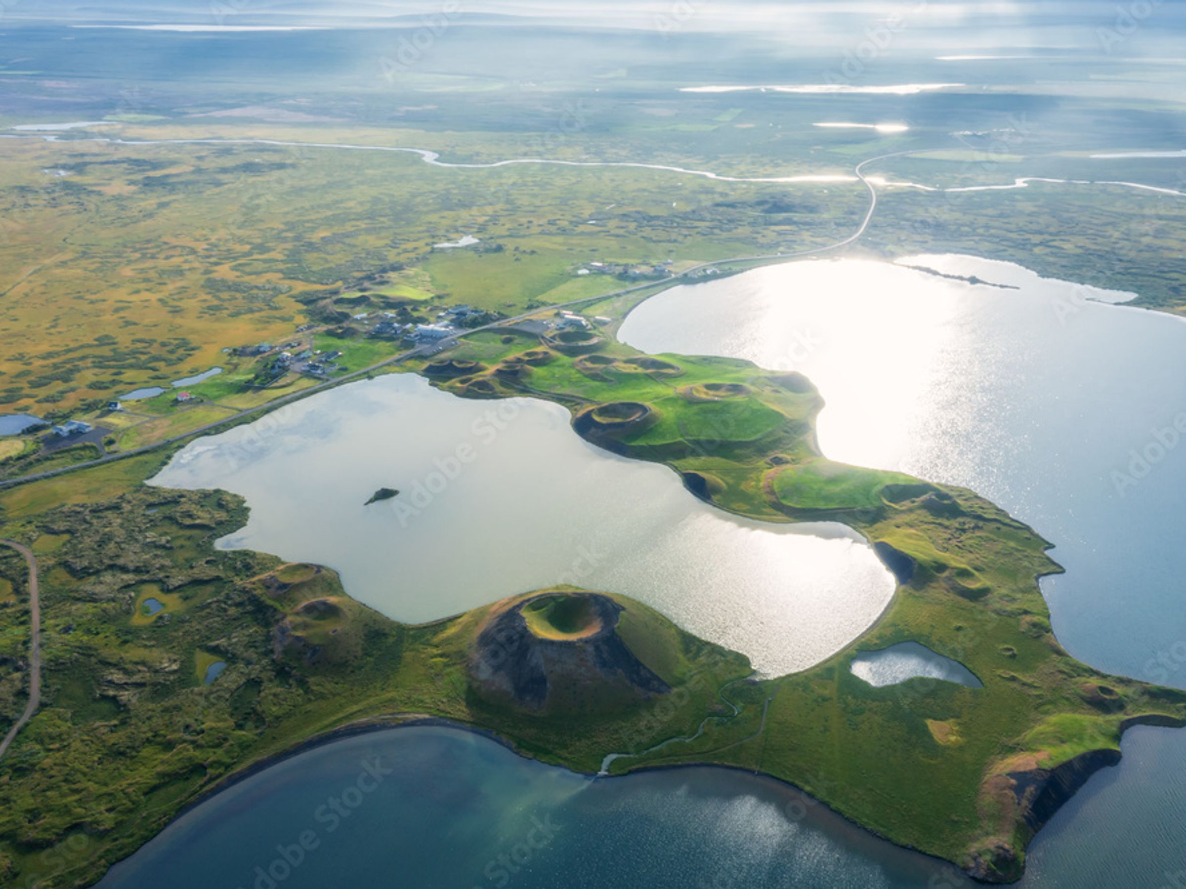 Aerial view of shimmering lakes, green landscapes, and numerous volcanic craters.