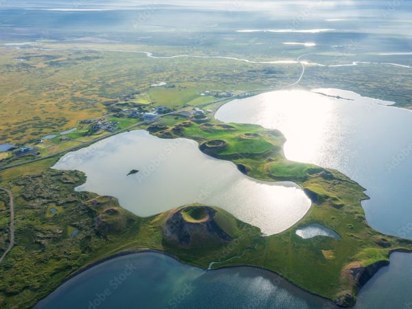 Aerial view of shimmering lakes, green landscapes, and numerous volcanic craters.