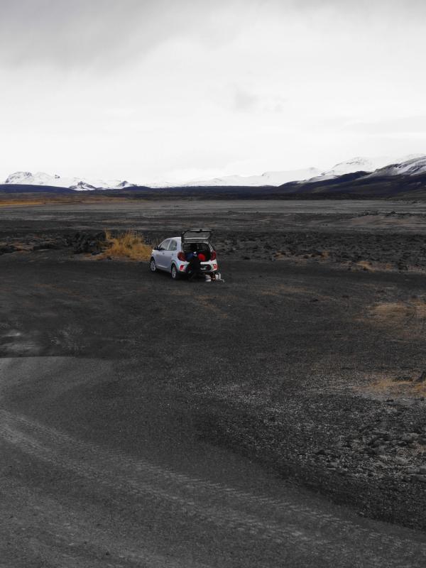 a white truck is parked in the middle of a dirt road .