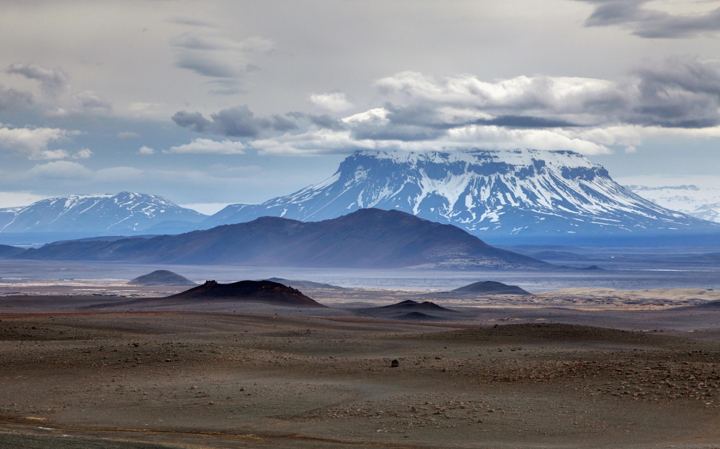 a desert landscape with mountains in the background and a cloudy sky .