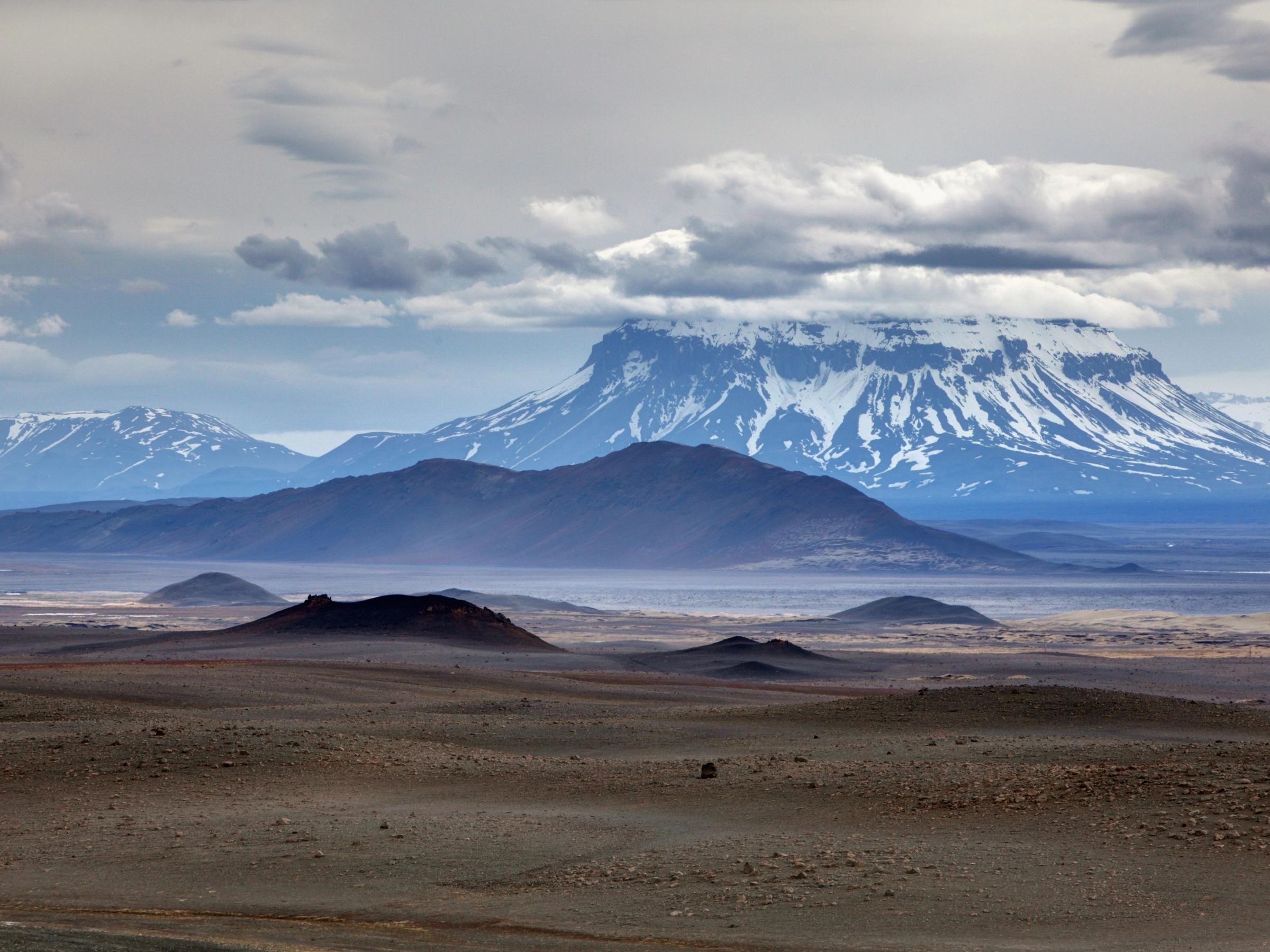 a desert landscape with mountains in the background and a cloudy sky .