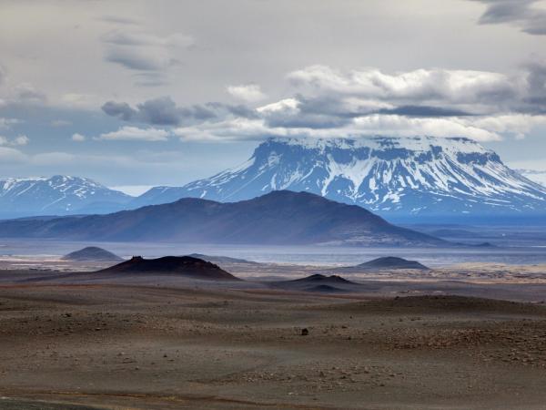 a desert landscape with mountains in the background and a cloudy sky .