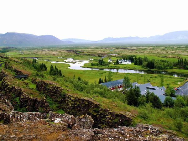 Vista de una valle con un río y montañas en el fondo