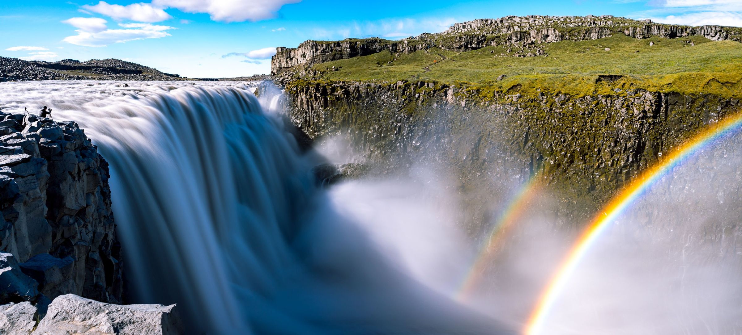 una cascada con un arcoíris en el fondo.