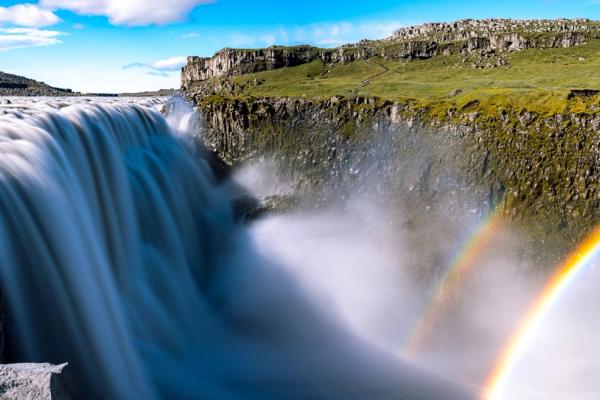 una cascada con un arcoíris en el fondo.