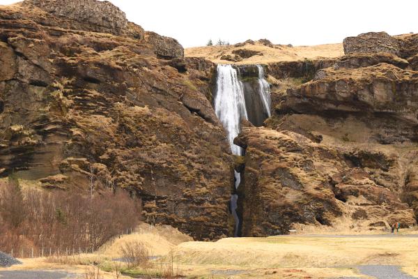a waterfall is surrounded by rocks and grass in the middle of a field .
