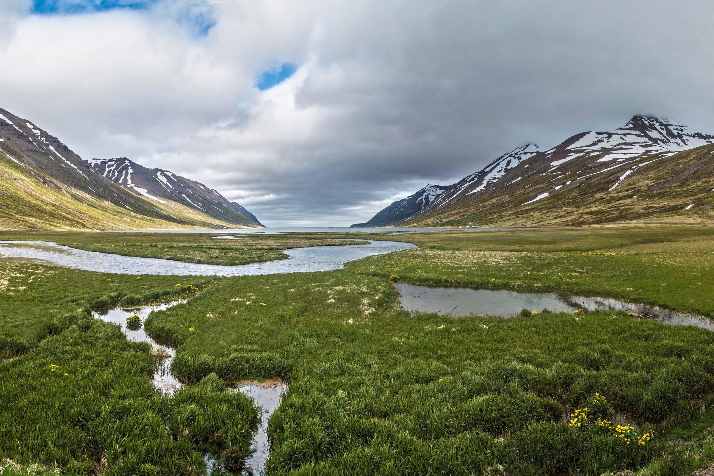a panoramic view of a valley with mountains in the background and a river running through it .