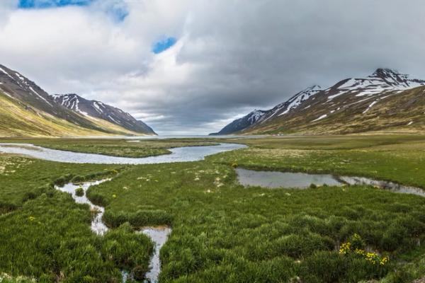 a panoramic view of a valley with mountains in the background and a river running through it .