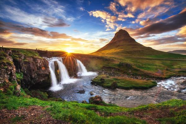 a waterfall with a mountain in the background at sunset at Kirkjufell in snæfellsnes in Iceland.