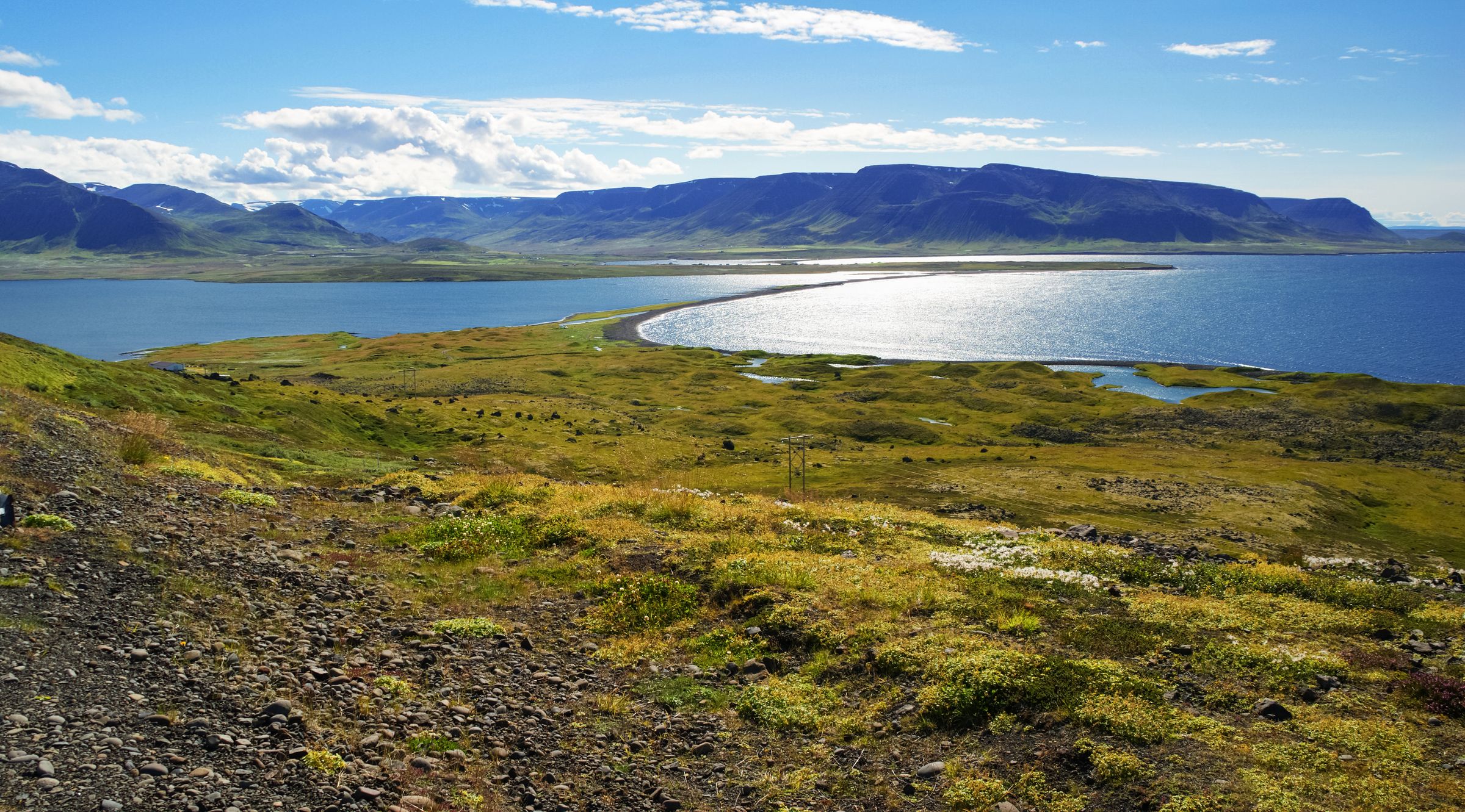 une vue d'un lac depuis une colline avec des montagnes en arrière-plan, péninsule de Tröllaskagi