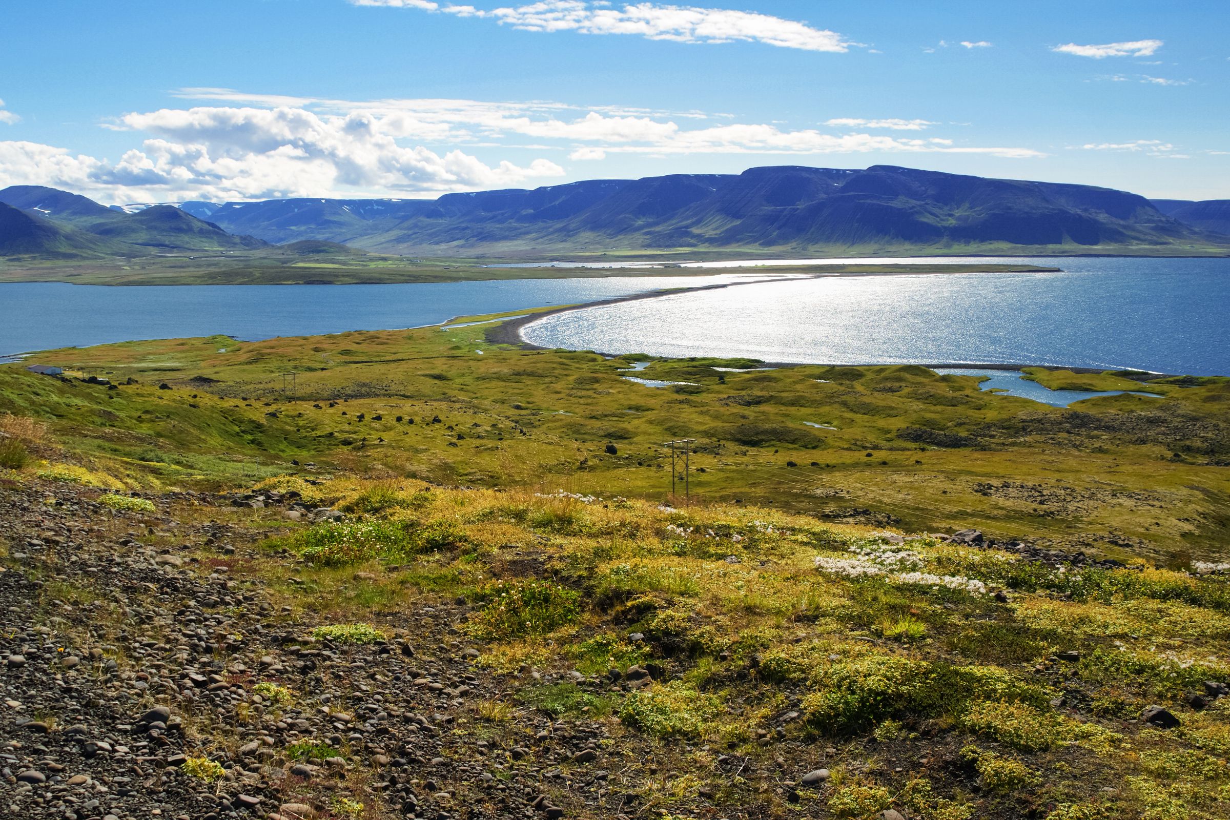une vue d'un lac depuis une colline avec des montagnes en arrière-plan, péninsule de Tröllaskagi