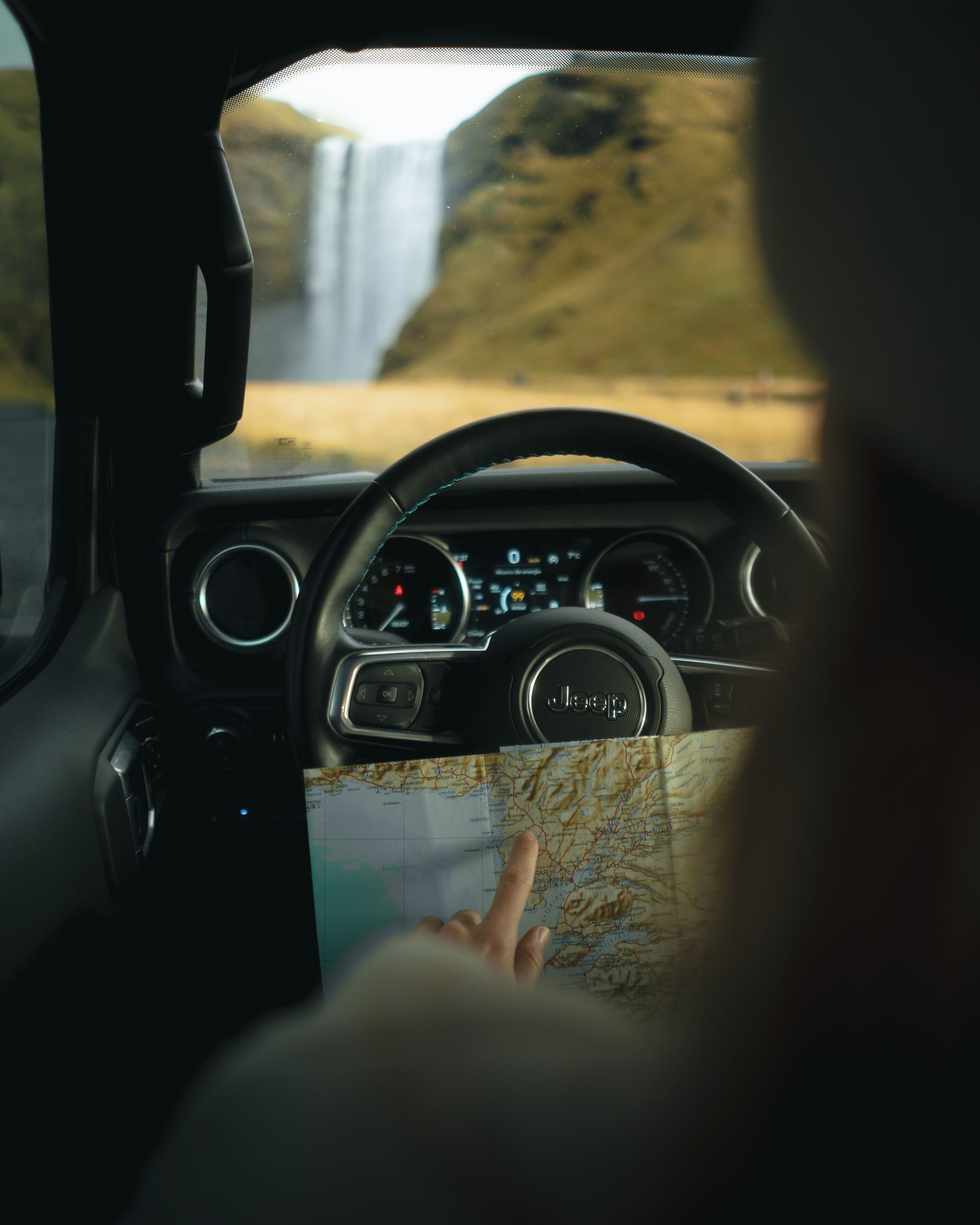 a person is driving a jeep and pointing at a map .