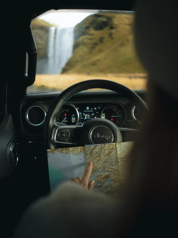 a person is driving a jeep and pointing at a map .