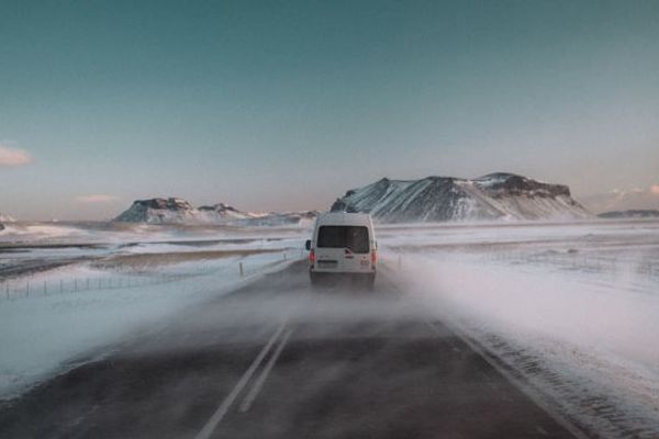 a white van is driving down a snowy road .