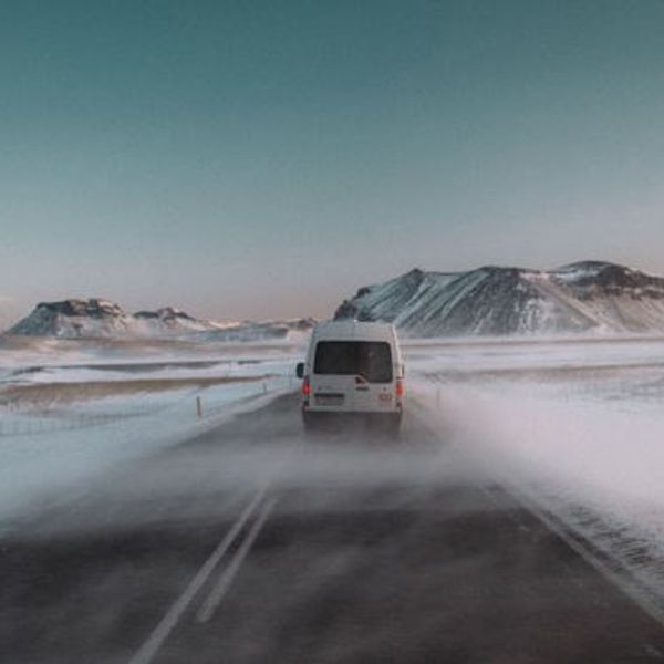 una furgoneta blanca está conduciendo por una carretera nevada.