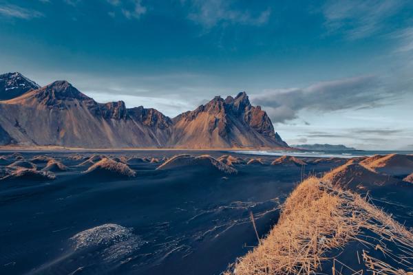 a desert landscape with mountains in the background and a blue sky in vestrahorn in iceland.