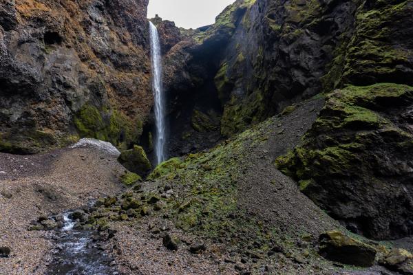a waterfall in the middle of a canyon surrounded by rocks and moss .
