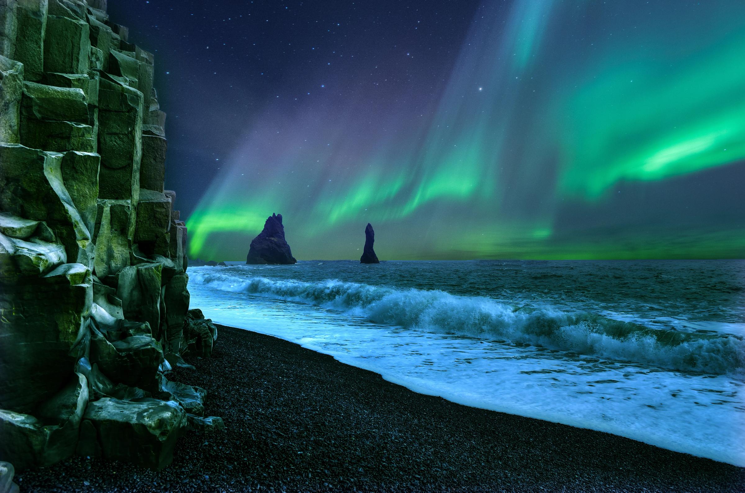 the aurora borealis is shining over the ocean at vík in south iceland.