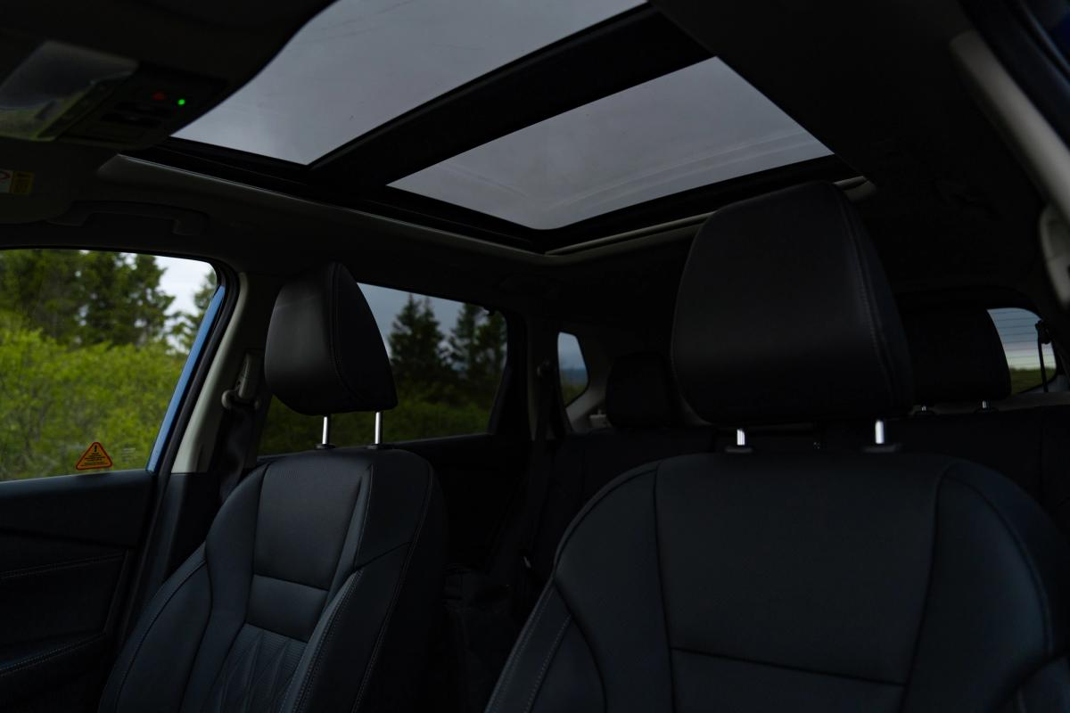 Vista interior del Nissan X-Trail con los asientos traseros y el techo solar panorámico abierto
