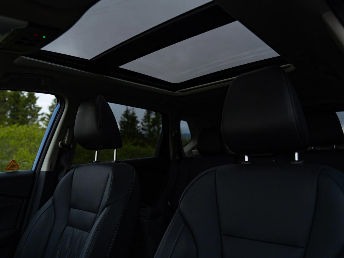 Interior del X-Trail con techo solar Vista interior del Nissan X-Trail con los asientos traseros y el techo solar panorámico abierto