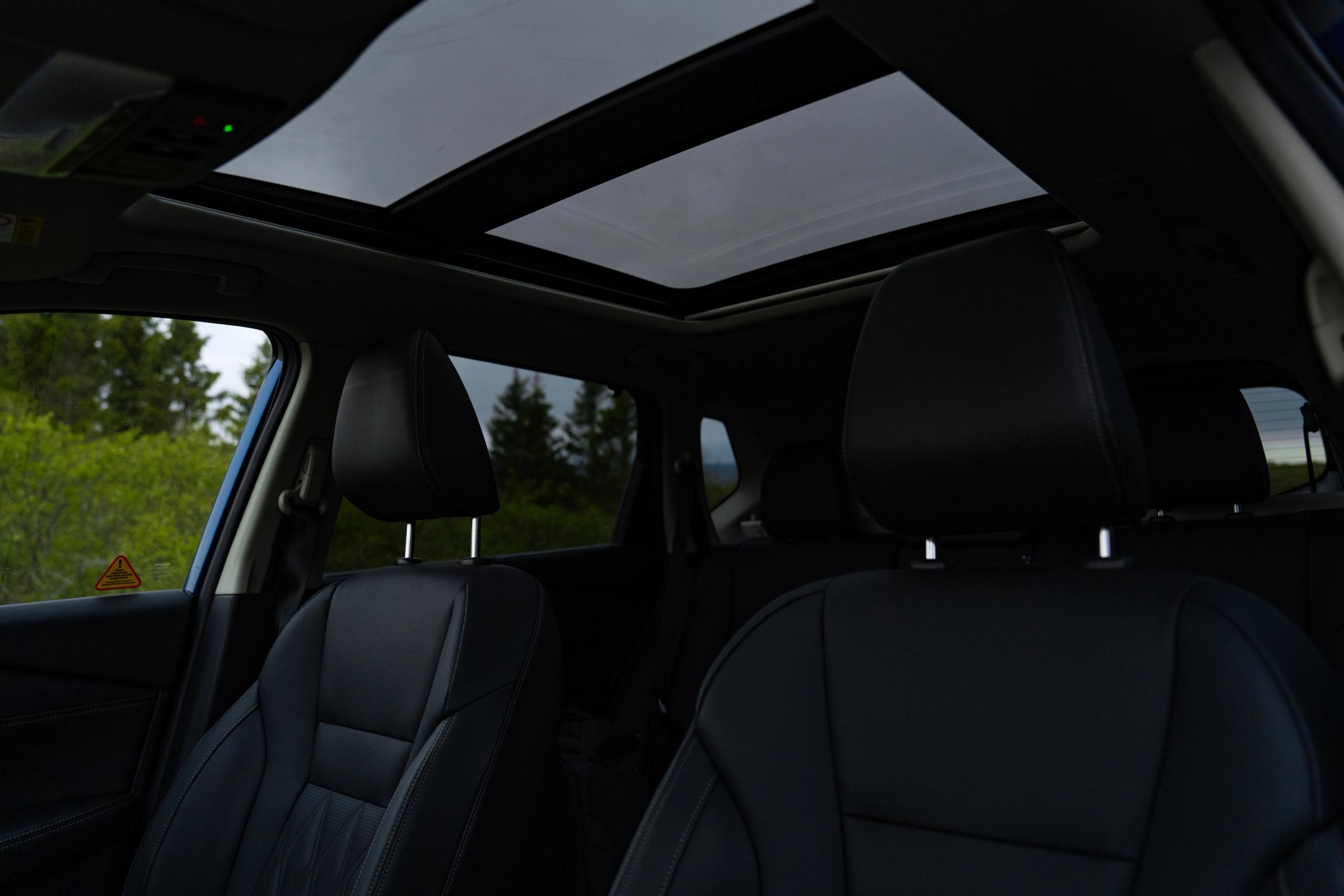Interior del X-Trail con techo solar Vista interior del Nissan X-Trail con los asientos traseros y el techo solar panorámico abierto