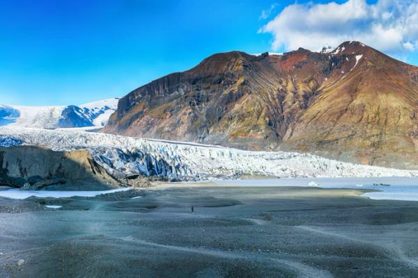a large glacier is surrounded by mountains and a river in iceland.