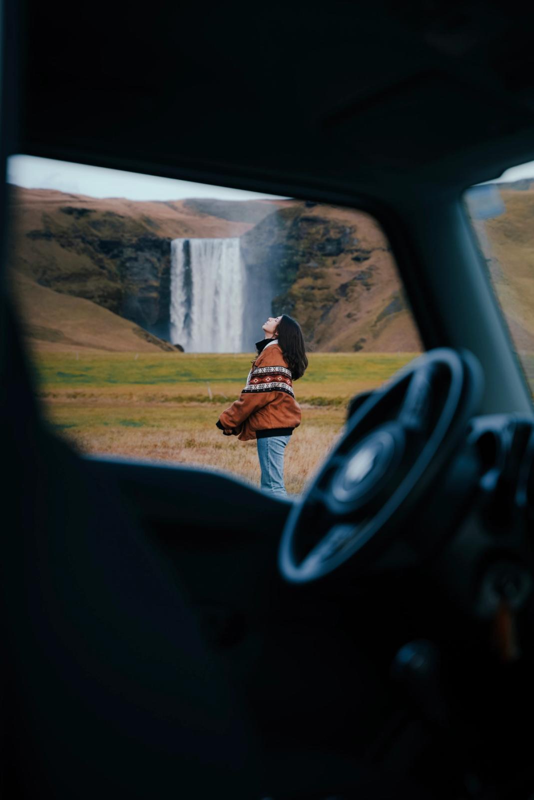 a woman is standing in front of a waterfall in a field .