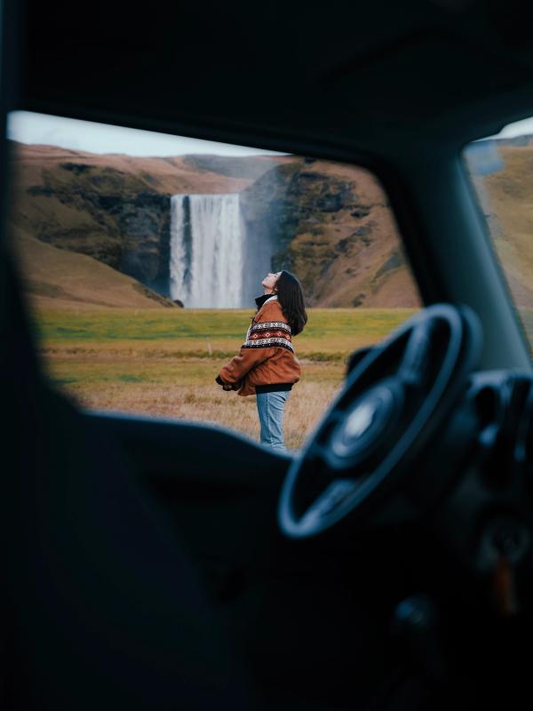 a woman is standing in front of a waterfall in a field .