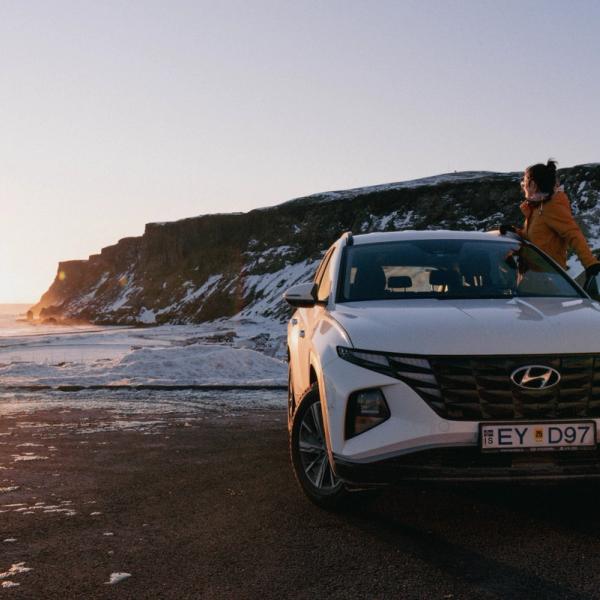 a woman is standing next to a white car on a snowy road .