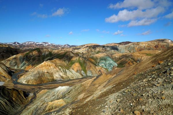 a river runs through a valley surrounded by mountains on a sunny day .