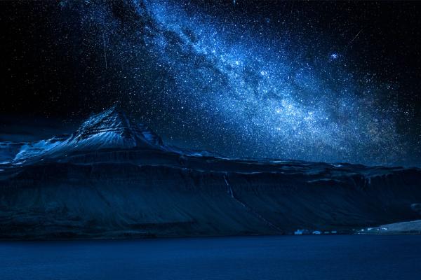a large iceberg is floating in the ocean under a starry night sky .