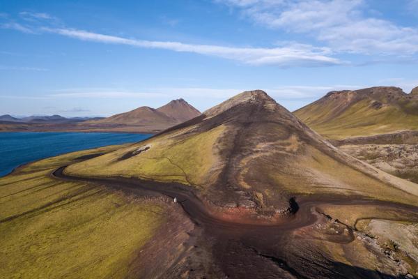 an aerial view of a mountain with a road going through it and a lake in the background .