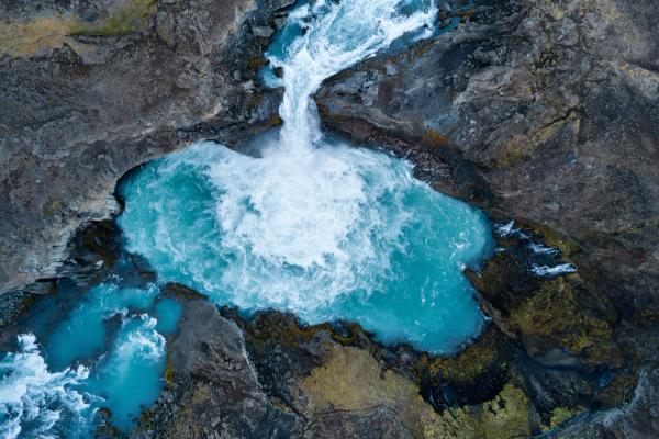 Aerial view of a turquoise waterfall cascading into a rocky pool.