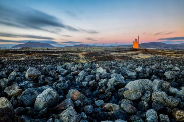 a large pile of rocks with a lighthouse in the background .