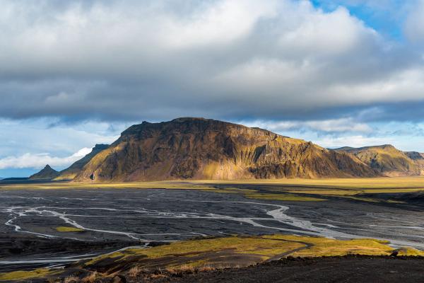 there is a mountain in the background and a river in the foreground .