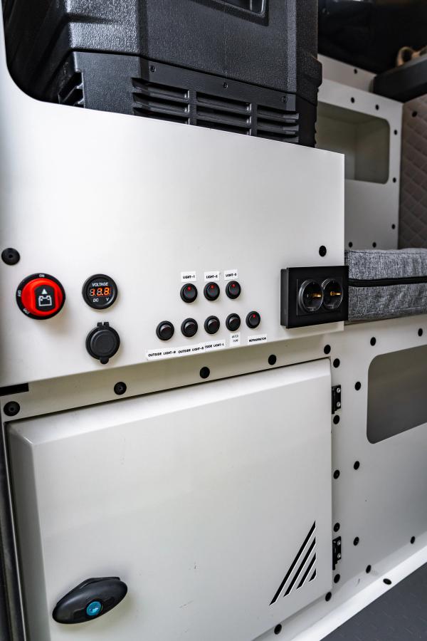 Panel con interruptor de batería, indicador de voltaje, toma de 12 V y enchufes debajo de la nevera portátil