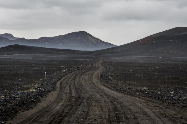 a dirt road in the middle of a desert with mountains in the background .