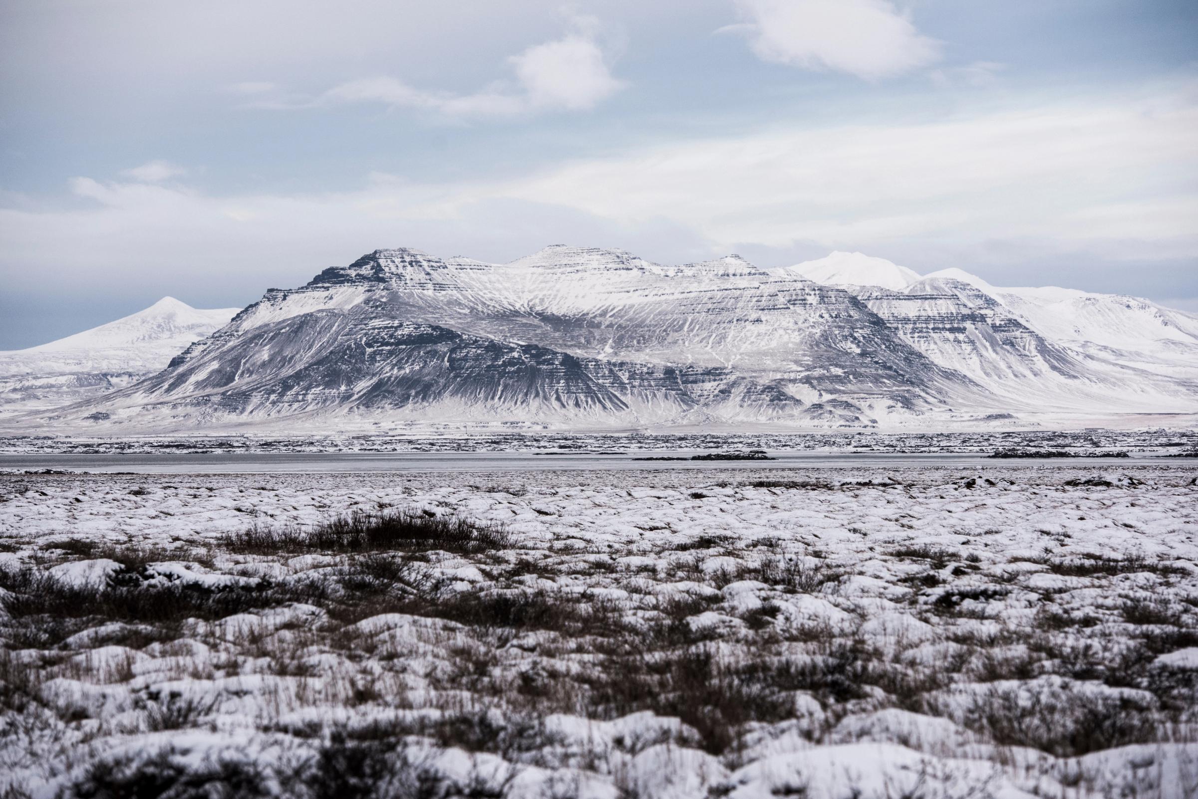 a snowy field with a mountain in the background .